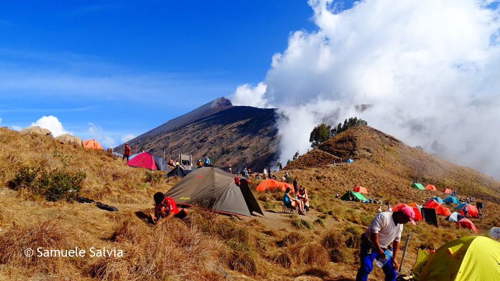 Il campo base del Monte Rinjani con la coloratissima distesa di tende. Sullo sfondo, minacciosa, la vetta del vulcano.